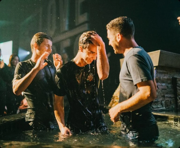 A man being baptized in the water with friends celebrating around him