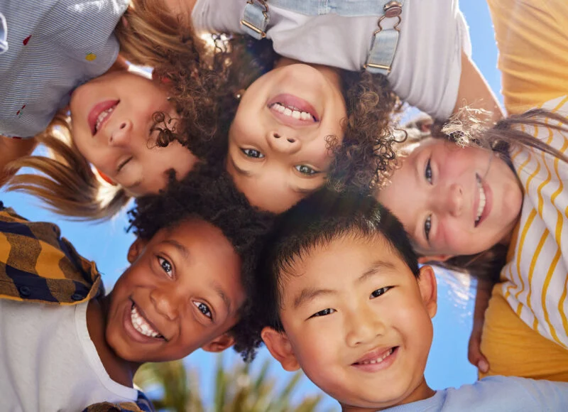 Smiling kids leaning in together in a circle