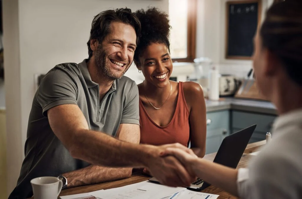 Smiling friends shaking hands across a table